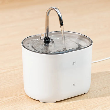 The KittyNook Cat Co. Cat Water Fountain Automatic Filter dispenses water for pets on a wooden surface.